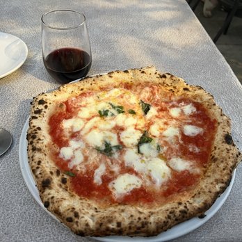Spacca Napoli Pizzeria signature dishes Margherita Pizza (DOC), Prosciutto e Rucola Pizza, various seasonal specialty pizzas, Pistachio Gelato.
